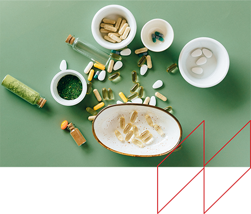 Assorted dietary supplements and medications, including capsules and tablets, scattered on a green surface, representing potential health risks associated with drugs like Elmiron linked to serious eye conditions.