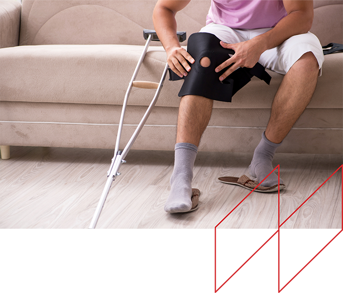 Man sitting on a couch with crutches, adjusting a knee brace, illustrating personal injury and negligence themes related to legal advocacy in Kentucky.