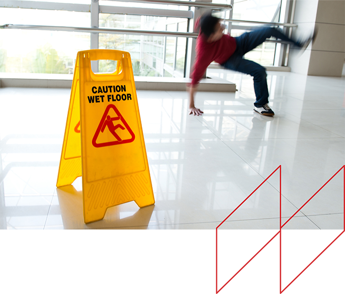 Caution wet floor sign in foreground with person slipping on a smooth surface, illustrating slip and fall hazards related to unsafe premises.