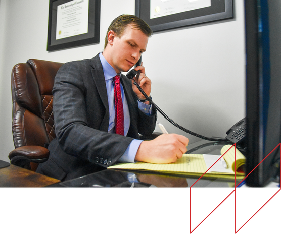 Alex White, Kentucky car accident lawyer, on phone and taking notes in office, emphasizing legal support for personal injury claims.