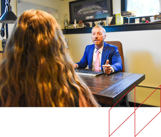 Professional consultation scene in a legal office, featuring a lawyer in a blue pinstripe suit and pink tie discussing defective product claims with a client, highlighting personal injury legal services.